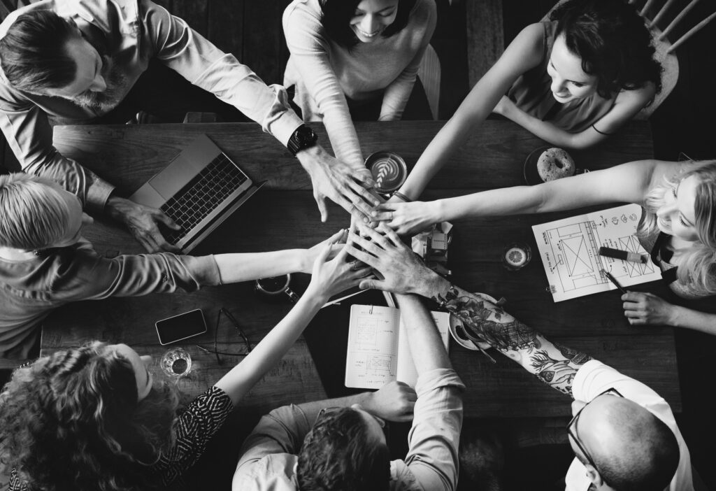 Group of eight people holding hands, symbolizing collaboration and support, representing RobocraftFX's commitment to helping traders succeed.